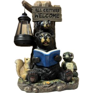 Decorative garden statue of a bear holding a blue book with woodland animals, lantern to the side, and a sign reading 'All Critters Welcome'