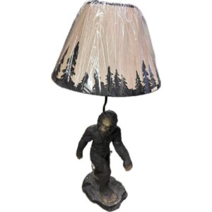 Decorative gorilla statue holding a large lava rock, in front of a beige cone lampshade wrapped in plastic wrap behind it.