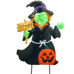 Halloween witch figurine in a black dress holding a 'Spooky' sign with a pumpkin detail on her skirt.